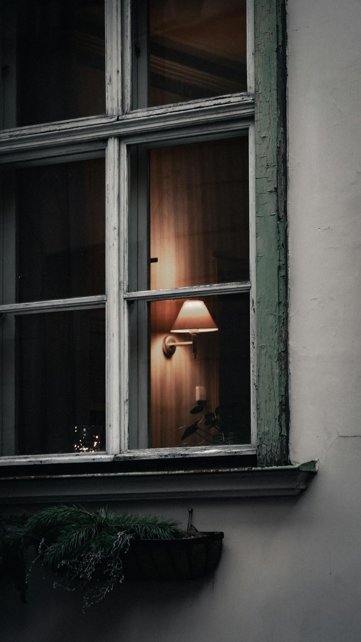 A warm lamp glowing through an old window — the kind of evening when you don't have a lot to say.